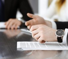 Unknown business people discussing questions of contract at meeting in modern office, close-up. Teamwork and partnership concept.